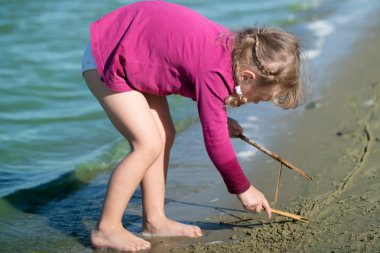 küçük kız kum üzerine çizer