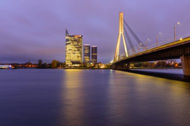 Riga, Letonya - 18 Ekim 2019: Daugava nehri ile Riga 'nın güzel şehri. Modern ofis binaları ve kablolu köprü