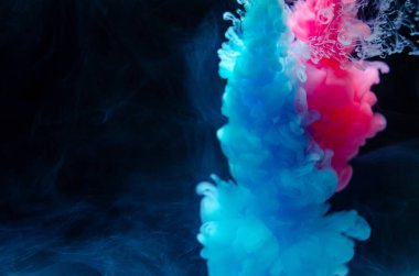 Suyun içinde çok renkli boyalar. Mürekkep suyun altında döner. Parlak mürekkep arka planında bir çarpışma bulutu. Soyut arkaplan