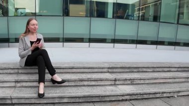 İş kadını merdivenlerde oturuyor ve cep telefonu kullanıyor. Yüksek kalite 4k görüntü