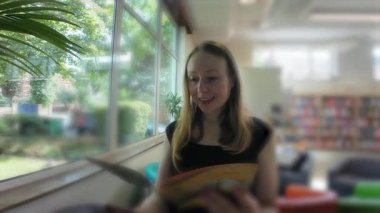 Kütüphanede broşürlere bakan genç bir kadın. Yüksek kalite 4k görüntü