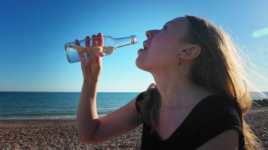 Bir kadın deniz kenarında ağır çekimde su içiyor. Yüksek kalite 4k görüntü