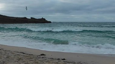 Dalgaları bekleyen sörfçülerle dolu bulutlu sahil dalgalı turkuaz sörfçülerle dolu.