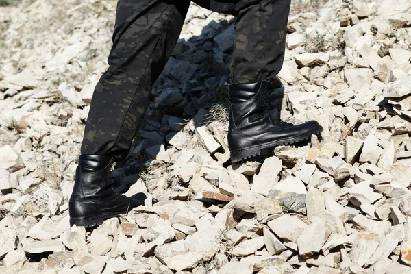 Man in black boots with laces and khaki pants on the background of nature. Caucasus, Russia