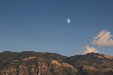 Hanın silueti ağaçlarla dolu yüksek bir dağın üzerinden yükseliyor. Yunanistan 'da Taygetus Dağı