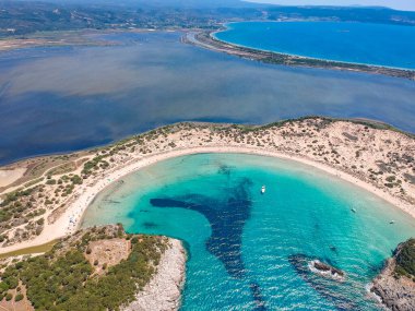 Voidokilia 'nın ünlü yarı dairesel kumlu plajı ve lagününün hava manzarası. Yunanistan 'ın Messenia kentinde kristal berrak turkuaz suyu bulunan Akdeniz' deki en ikonik plajlardan biridir.