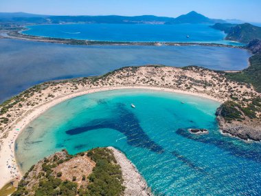 Voidokilia 'nın ünlü yarı dairesel kumlu plajı ve lagününün hava manzarası. Yunanistan 'ın Messenia kentinde kristal berrak turkuaz suyu bulunan Akdeniz' deki en ikonik plajlardan biridir.