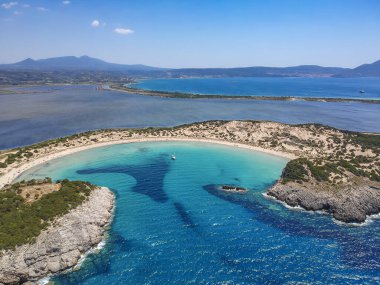 Voidokilia 'nın ünlü yarı dairesel kumlu plajı ve lagününün hava manzarası. Yunanistan 'ın Messenia kentinde kristal berrak turkuaz suyu bulunan Akdeniz' deki en ikonik plajlardan biridir.