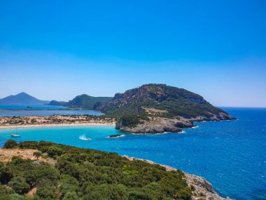 Voidokilia 'nın ünlü yarı dairesel kumlu plajı ve lagününün hava manzarası. Yunanistan 'ın Messenia kentinde kristal berrak turkuaz suyu bulunan Akdeniz' deki en ikonik plajlardan biridir.