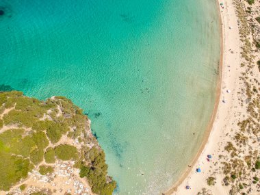 Voidokilia 'nın ünlü yarı dairesel kumlu plajı ve lagününün hava manzarası. Yunanistan 'ın Messenia kentinde kristal berrak turkuaz suyu bulunan Akdeniz' deki en ikonik plajlardan biridir.
