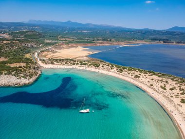 Voidokilia 'nın ünlü yarı dairesel kumlu plajı ve lagününün hava manzarası. Yunanistan 'ın Messenia kentinde kristal berrak turkuaz suyu bulunan Akdeniz' deki en ikonik plajlardan biridir.
