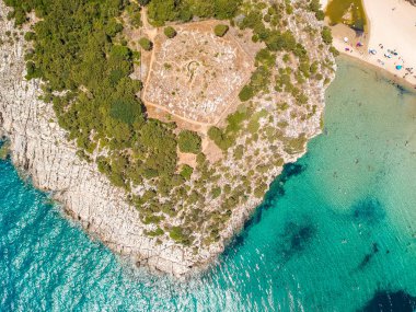 Voidokilia 'nın ünlü yarı dairesel kumlu plajı ve lagününün hava manzarası. Yunanistan 'ın Messenia kentinde kristal berrak turkuaz suyu bulunan Akdeniz' deki en ikonik plajlardan biridir.