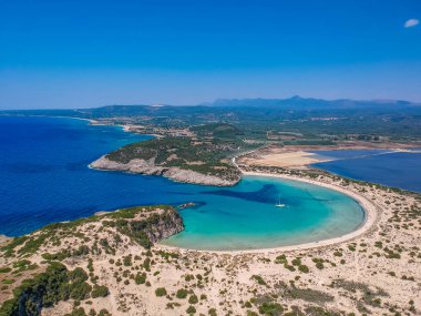 Voidokilia 'nın ünlü yarı dairesel kumlu plajı ve lagününün hava manzarası. Yunanistan 'ın Messenia kentinde kristal berrak turkuaz suyu bulunan Akdeniz' deki en ikonik plajlardan biridir.