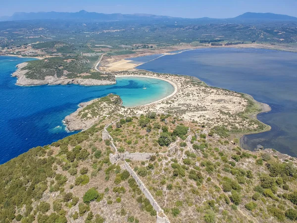 Voidokilia 'nın ünlü yarı dairesel kumlu plajı ve lagününün hava manzarası. Yunanistan 'ın Messenia kentinde kristal berrak turkuaz suyu bulunan Akdeniz' deki en ikonik plajlardan biridir.