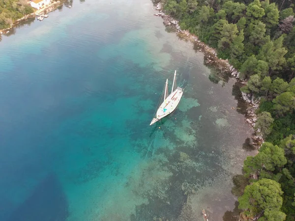 Aerial view of a wooden sailing boat anchored in a small picturesque harbor. Amazing Greek beauty of Skopelos, Greece