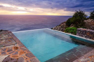 Peloponnesos 'un güney kıyısında kayalarla çevrili güzel bir manzarası olan sonsuz havuzun arkasında güzel bir gün batımı. Yunanistan 'ın Laconia kentindeki Tenaron Burnu yakınlarındaki şaşırtıcı doğal manzara.