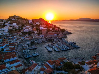 Hava aracı, gün batımında pitoresk liman ve Hydra (veya Ydra) adasının ana köyünün panoramik fotoğrafını çeker. Hydra, Yunanistan 'ın Saronik Körfezi' nde bulunan neoklasik evleri ile önde gelen turizm merkezlerinden biri..