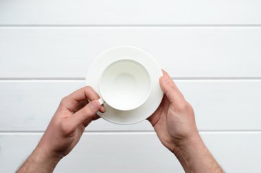 Beyaz bir bardak tutan bir erkek eli resmini