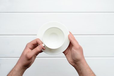 Beyaz bir bardak tutan bir erkek eli resmini