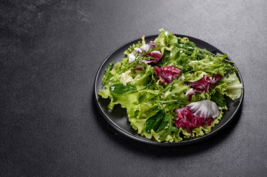 Koyu beton arka planda bir tabakta doğranmış sebze salatası.