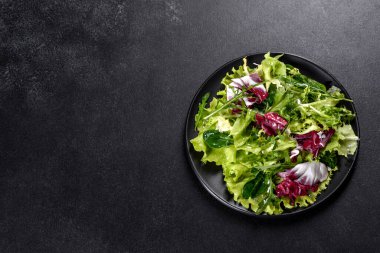 Koyu beton arka planda bir tabakta doğranmış sebze salatası.