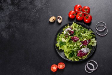 Koyu beton arka planda bir tabakta doğranmış sebze salatası.