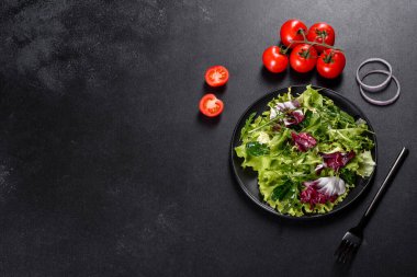 Koyu beton arka planda bir tabakta doğranmış sebze salatası.