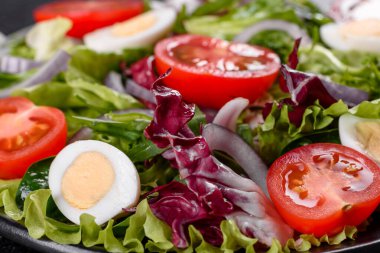 Koyu beton arka planda bir tabakta doğranmış sebze salatası.