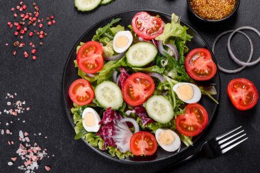 Koyu beton arka planda bir tabakta doğranmış sebze salatası.