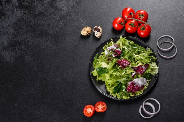 Koyu beton arka planda bir tabakta doğranmış sebze salatası.