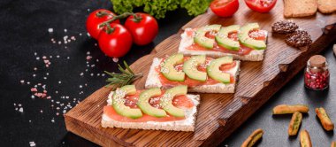 Koyu beton bir masada kırmızı balık, tereyağı, ekmek ve avokado ile nefis taze sandviç.