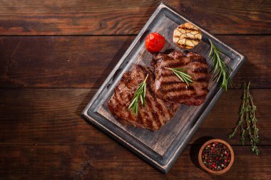 Karanlık bir arka planda taze sulu lezzetli biftek. Baharatlı ve otlu et yemeği.