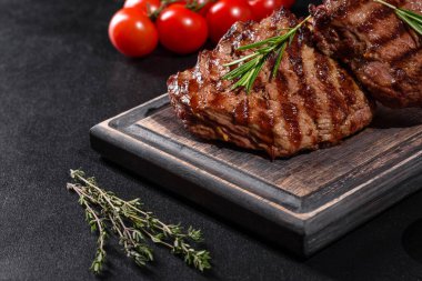 Karanlık bir arka planda taze sulu lezzetli biftek. Baharatlı ve otlu et yemeği.