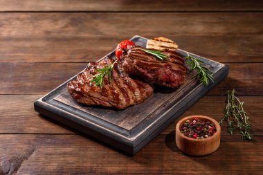 Karanlık bir arka planda taze sulu lezzetli biftek. Baharatlı ve otlu et yemeği.