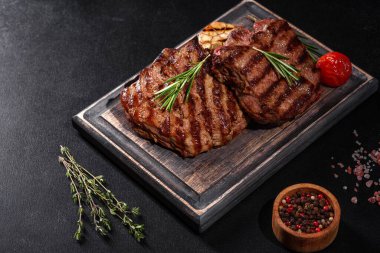 Karanlık bir arka planda taze sulu lezzetli biftek. Baharatlı ve otlu et yemeği.