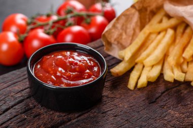 Tahta kesme tahtasında taze patates kızartması ve kırmızı sos. Sağlıksız yemek, fast food