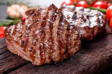 Karanlık bir arka planda taze sulu lezzetli biftek. Baharatlı ve otlu et yemeği.