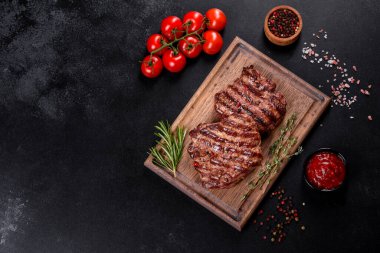 Karanlık bir arka planda taze sulu lezzetli biftek. Baharatlı ve otlu et yemeği.