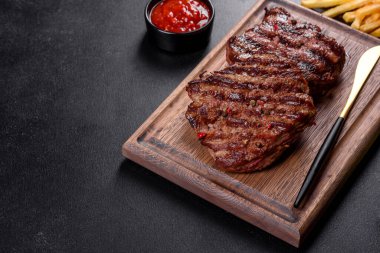 Karanlık bir arka planda taze sulu lezzetli biftek. Baharatlı ve otlu et yemeği.