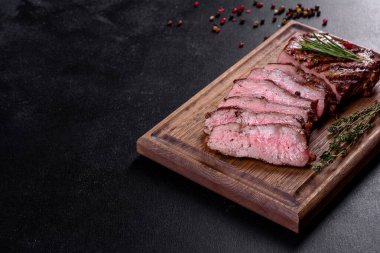 Karanlık bir arka planda taze sulu lezzetli biftek. Baharatlı ve otlu et yemeği.