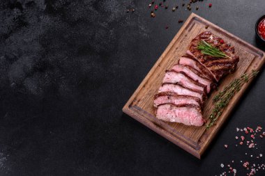 Karanlık bir arka planda taze sulu lezzetli biftek. Baharatlı ve otlu et yemeği.