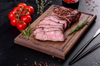 Karanlık bir arka planda taze sulu lezzetli biftek. Baharatlı ve otlu et yemeği.