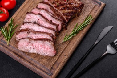 Karanlık bir arka planda taze sulu lezzetli biftek. Baharatlı ve otlu et yemeği.