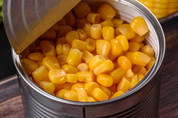 Fresh delicious loose canned corn on a wooden cutting board on a dark concrete background