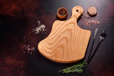 Koyu beton arka planda tuz, baharat ve otlarla tahta kesmek. Sağlıklı Yemek Pişirme