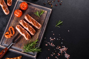 Sebze, baharat ve otlarla ızgara yapılmış lezzetli, taze sosisler. Bitmiş tabağın koyu beton bir masada fotoğrafı.