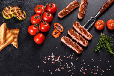 Sebze, baharat ve otlarla ızgara yapılmış lezzetli, taze sosisler. Bitmiş tabağın koyu beton bir masada fotoğrafı.