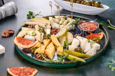 Dört çeşit peynir kesmek: keçiler, parmesan peyniri, camembert peyniri ve armut ve kurutulmuş greyfurt dilimleri ve mikro yeşillikler. Lezzetli sağlıklı atıştırmalık