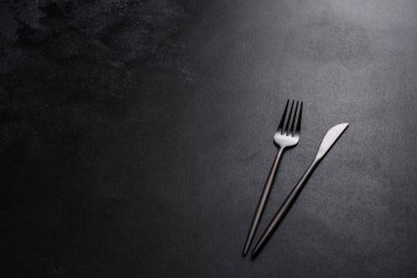 Beton bir masada siyah çatal bıçak takımı. Yemek masası hazırlığı