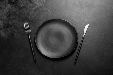 Beton bir masada siyah çatal bıçak takımı. Yemek masası hazırlığı